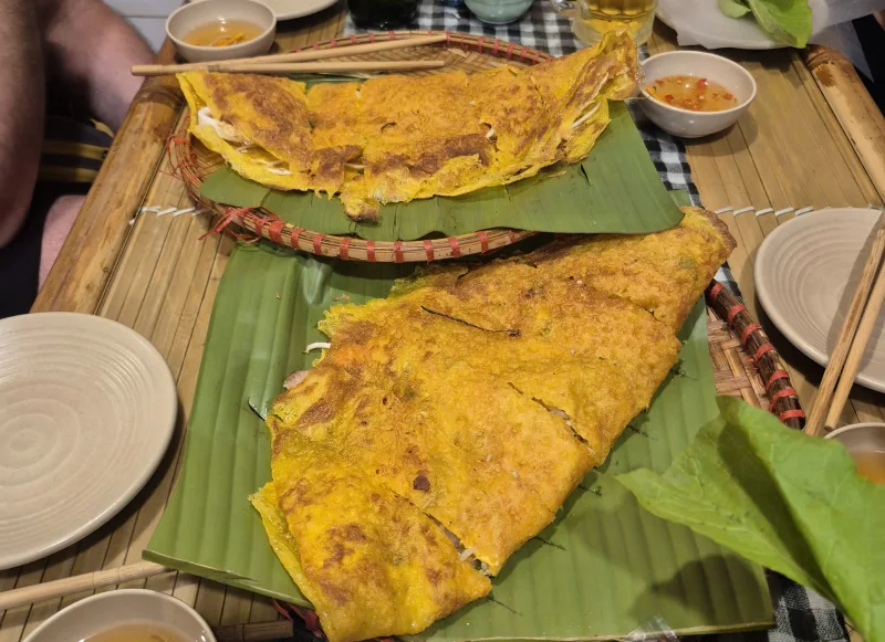 A crispy Vietnamese pancake (banh xeo) filled with herbs and vegetables, served as street food in Hanoi