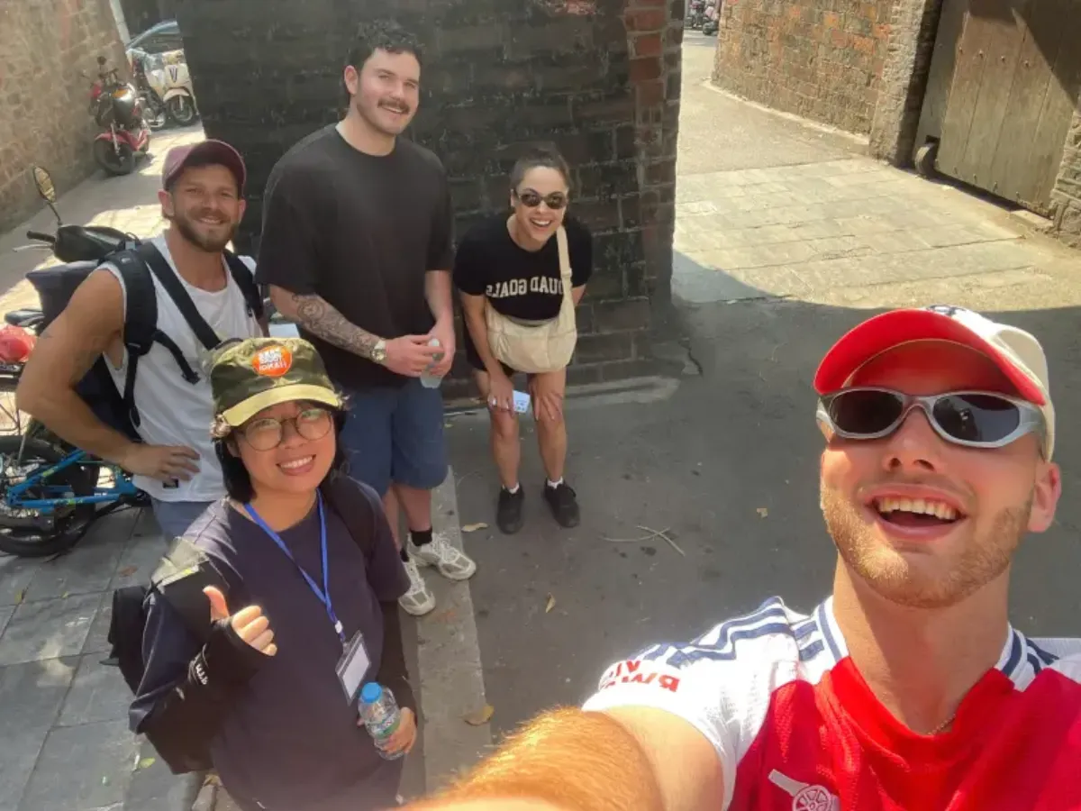 Group of travelers on a Hanoi private tour taking a selfie with a local guide in the Old Quarter