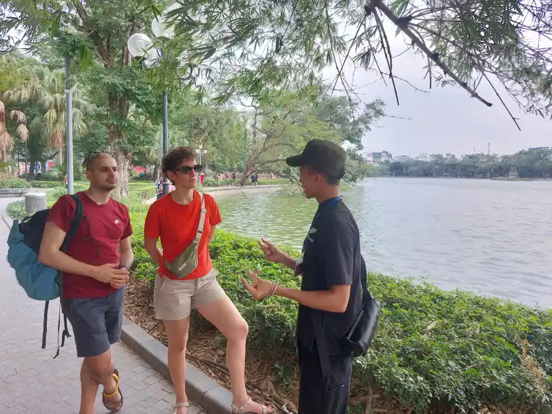 Local guide sharing stories with travelers during a Hanoi private walking tour by the lake