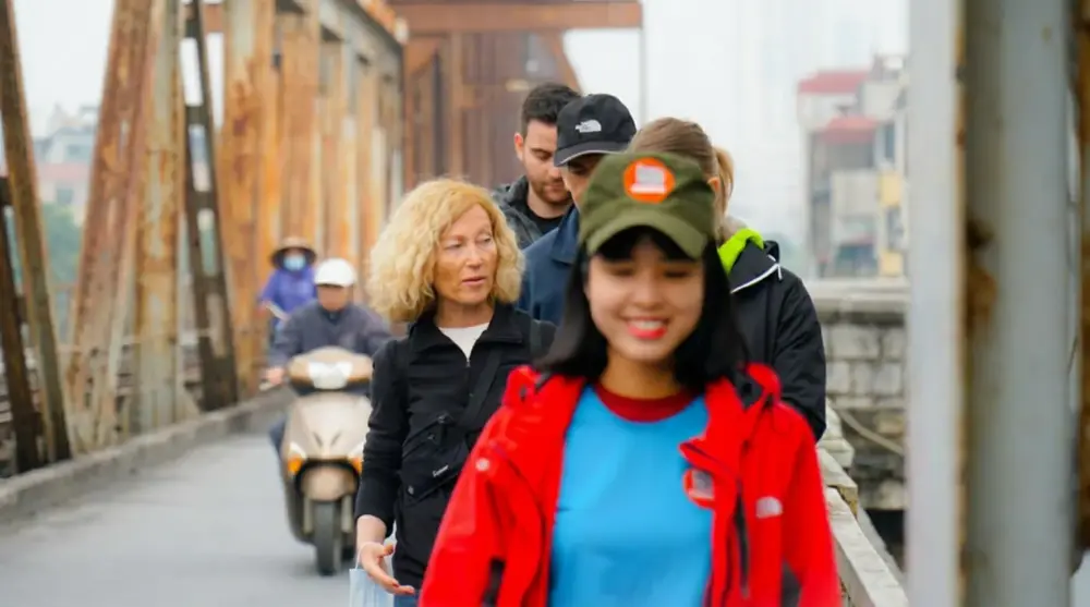 Walking tour group crossing Long Bien Bridge in Hanoi with local guide