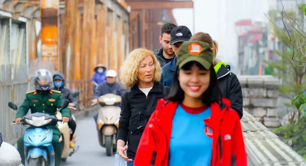 Walking tour group crossing Long Bien Bridge in Hanoi with local guide